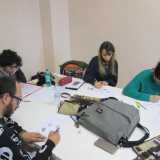 Intorno a un tavolo seguiamo i ragazzi disegnare mentre ascoltano la lezione del docente
